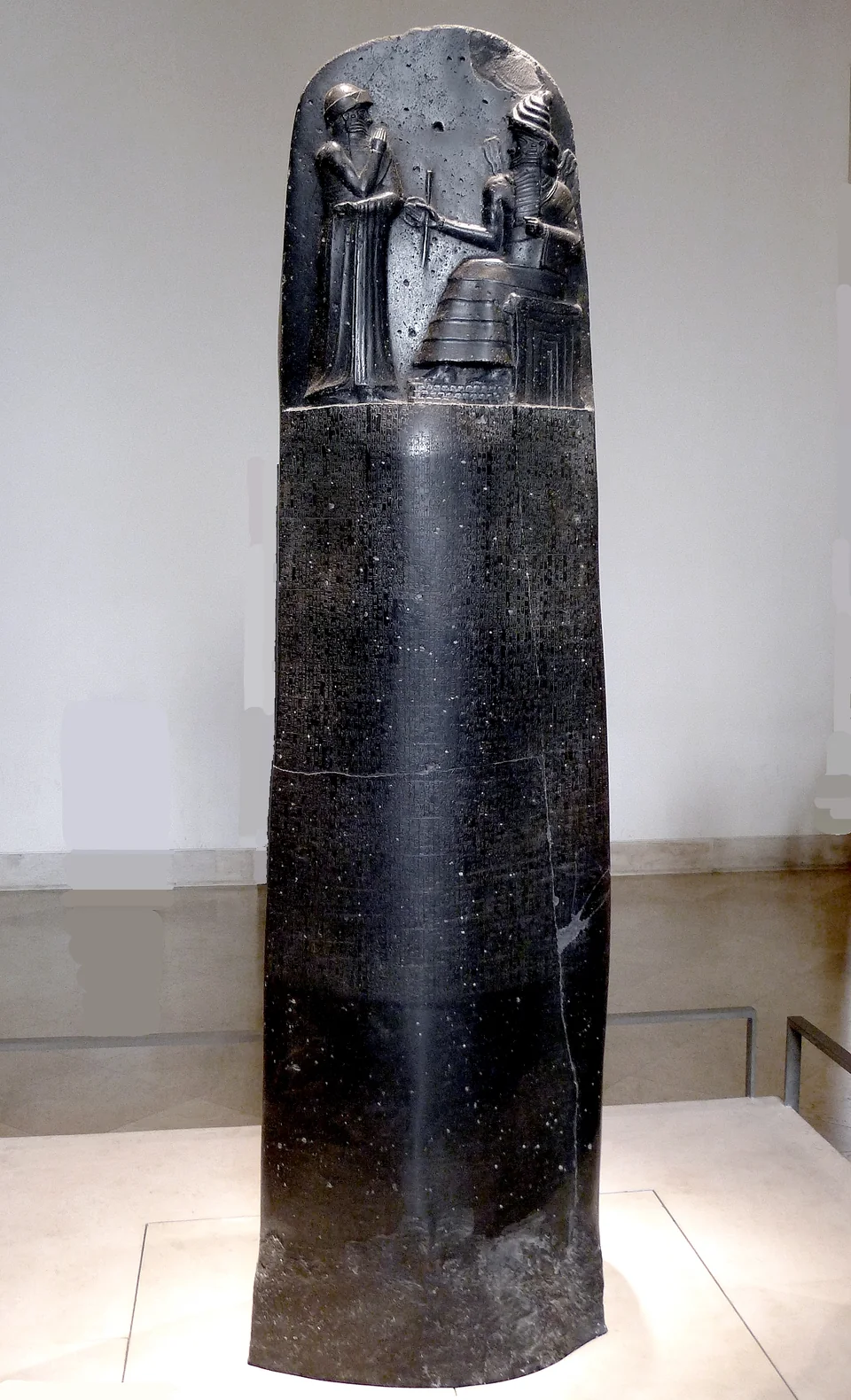 La stele delle leggi di Hammurabi, un alto monolito di pietra scura la cui sommità porta un rilievo con due figure, mentre il resto della superficie è coperto di colonne di segni cuneiformi.