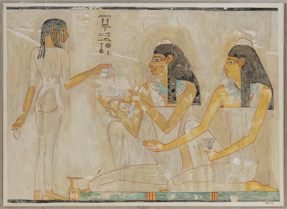 Deux invitées et une jeune fille servant un liquide dans un fac-similé d’une scène de la tombe de Rekhmire.